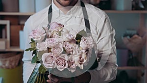 Close up view of florist preparing flower composition at workplace,bouquet of roses peone and lilac for valentine`s day
