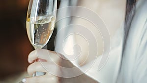 Close-up view of foaming glass with champagne in the hands of a european brunette bride with long hair in a wedding