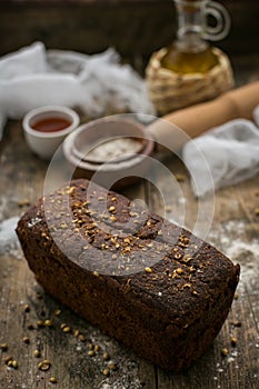 Close up view of fresh brown crispy loaf of bread lying on the wooden table sprinkled with flour.