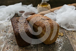 Close up view of fresh brown crispy loaf of bread lying on the wooden table sprinkled with flour.