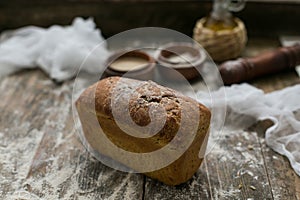 Close up view of fresh brown crispy loaf of bread lying on the wooden table sprinkled with flour