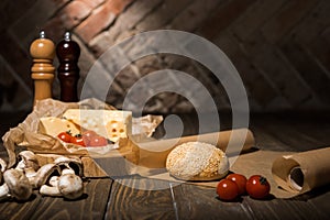 close up view of fresh cherry tomatoes, cheese, mushrooms and loaf of bread on baking paper