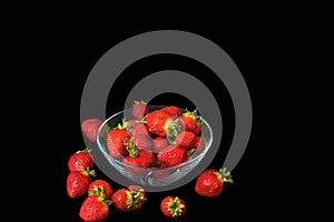 Close up view of fresh red strawberry in glass bowl on blackbackground.