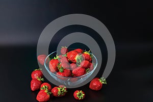 Close up view of fresh red strawberry in glass bowl on blackbackground. photo