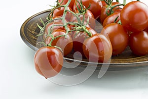 Close up view of fresh red tomatoes bunch in a plate on a white background