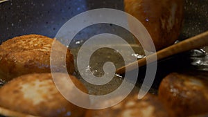 Close-Up View of Fried Donuts Being Picked From Boiling Pan with fork and spoon