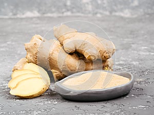 Ginger poder and ginger root on gray background photo