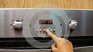 Close up view of girl hand setting up the timer delay for baking at the kitchen