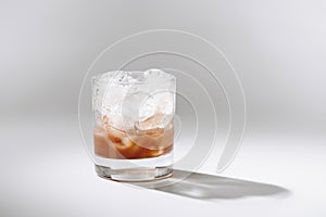 close up view of glass of cold brewed coffee with ice cubes on white tabletop