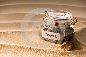 close up view of glass jar with dollars on sandy beach with seashells