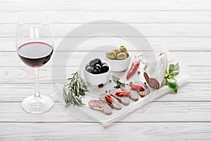 Close up view of glass of red wine, olives and assorted meat snacks