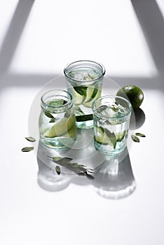 close up view of glasses with water, lime pieces and ice cubes