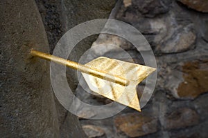 Close-up view of a golden arrow stuck in a stone.