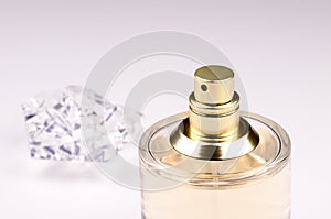 Close-up view of golden glass bottle perfume with spray on white