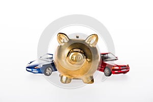 close-up view of golden piggy bank and small cars