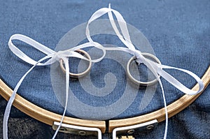 Close-up view of golden wedding rings on blank decorative stiching ring pillow