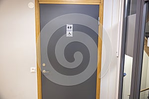 Close up view of gray door of public toilet with sign for men ,women and disabled or handicapped. Sweden.