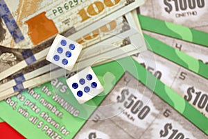 Close up view of green lottery scratch cards with us dollar bills and dice. Many used fake instant lottery tickets with gaming