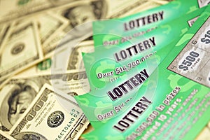 Close up view of green lottery scratch cards and us dollar bills. Many used fake instant lottery tickets with gambling results.