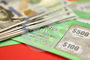 Close up view of green lottery scratch cards and us dollar bills. Many used fake instant lottery tickets with gambling results.