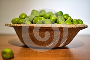 De cerca de verde tacones altos o rizos o aceituna semillas o en pequeno de madera un tazón blanco 