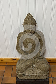 Close up view of grey buddah figure on white wall background