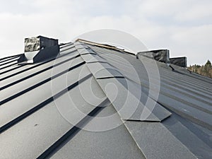 close up view of grey folding roof and chimney on waterproofing layer of house under construction