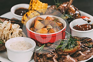 close-up view of grilled vegetables, roasted chicken wings and beef steaks with potatoes on plate