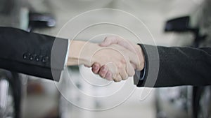 Close up view of hand giving a car keys to male hand in the car dealership. And shaking hands. A man gives keys to auto