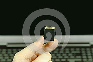 Close-up view of a hand holding a black SD memory card with a ba