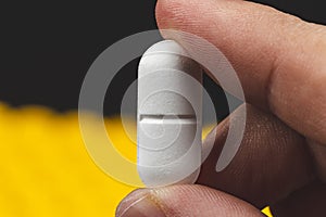 close up view of a hand holding a white pill - health care concept