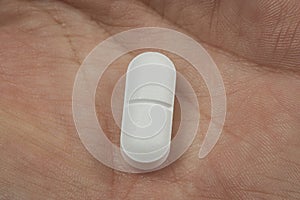 close up view of a hand holding a white pill - health care concept