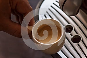 Close up view of the hand of a man working in a coffee house preparing espresso coffee waiting for the coffee machine to finish p