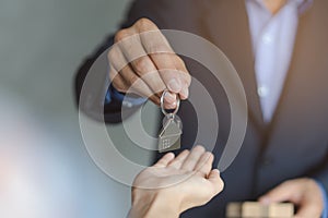 Close up view hand of property realtor / landlord giving key house to buyer .