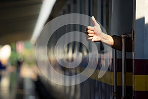 Close up view of a hand thumb up during departure of a train .