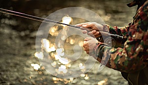 Close-up view of the hands of a fly fisherman working the line and the fishing rod