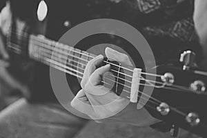 Close up view of hands playing guitar in black and white. Young woman playing guitar.