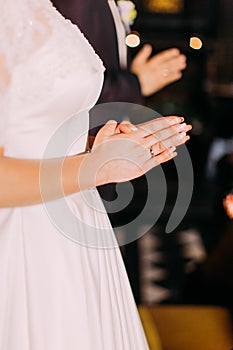 The close-up view of the hands of the praying bride.