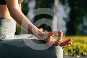 Close-up view of hands of young woman holding fingers on knee in yoga mudra position