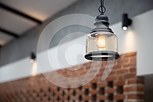 Close up view of hanging vintage ceiling yellow lamp and brick wall interior