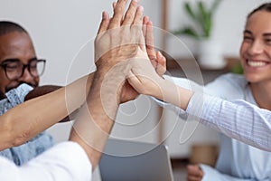 Close up view happy diverse business team giving high five photo