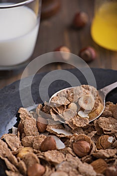 Close up view of healthy breakfast with nuts and corn flakes on brown rustic background