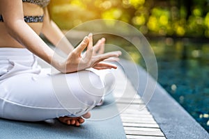 Close up view of her hands and crossed legs in the lotus position, woman training yoga and meditation in a lotus yoga position