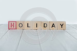 close up view of holiday word made of wooden cubes on white wooden tabletop