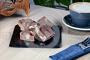 Close up view on homemade chocolate Fudge sugar candy with coffee on wooden table.