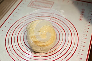 Close-up view of the homemade raw wheat dough ball lying on the modern cooking surface. Dough for pizza, pasta, potstickers.