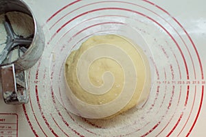 Close-up view of the homemade raw wheat dough ball lying on the modern cooking surface. Dough for pizza, pasta, potstickers.