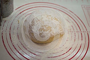 Close-up view of the homemade raw wheat dough ball lying on the modern cooking surface. Dough for pizza, pasta, potstickers.