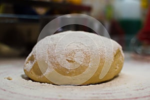 Close-up view of the homemade raw wheat dough ball lying on the modern cooking surface. Dough for pizza, pasta, potstickers.