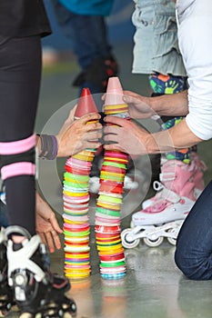 Close up view of human hands building plastic color cones on rollerskating playground